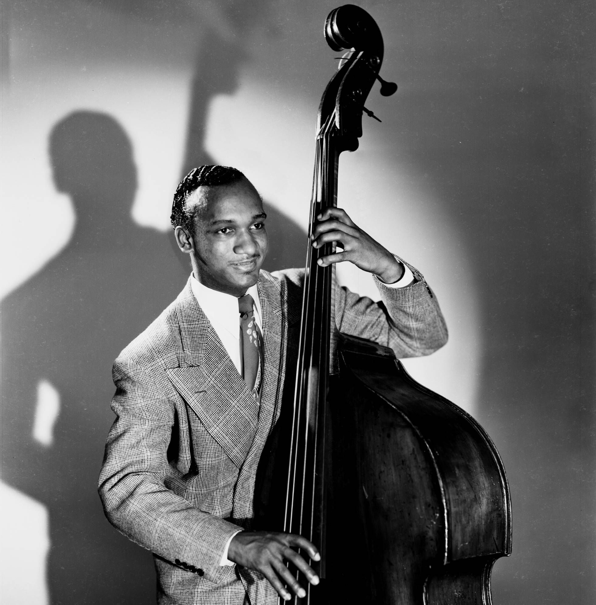 Oscar Petitford holding his bass, with his shadow on the wall